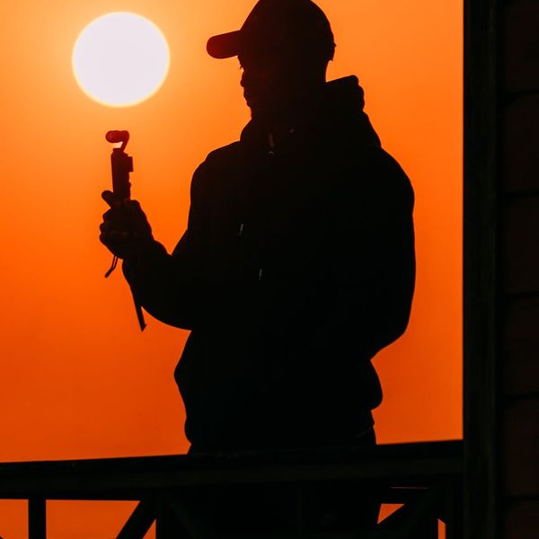 A person stretching outdoors with the sun setting behind them, creating a silhouette.